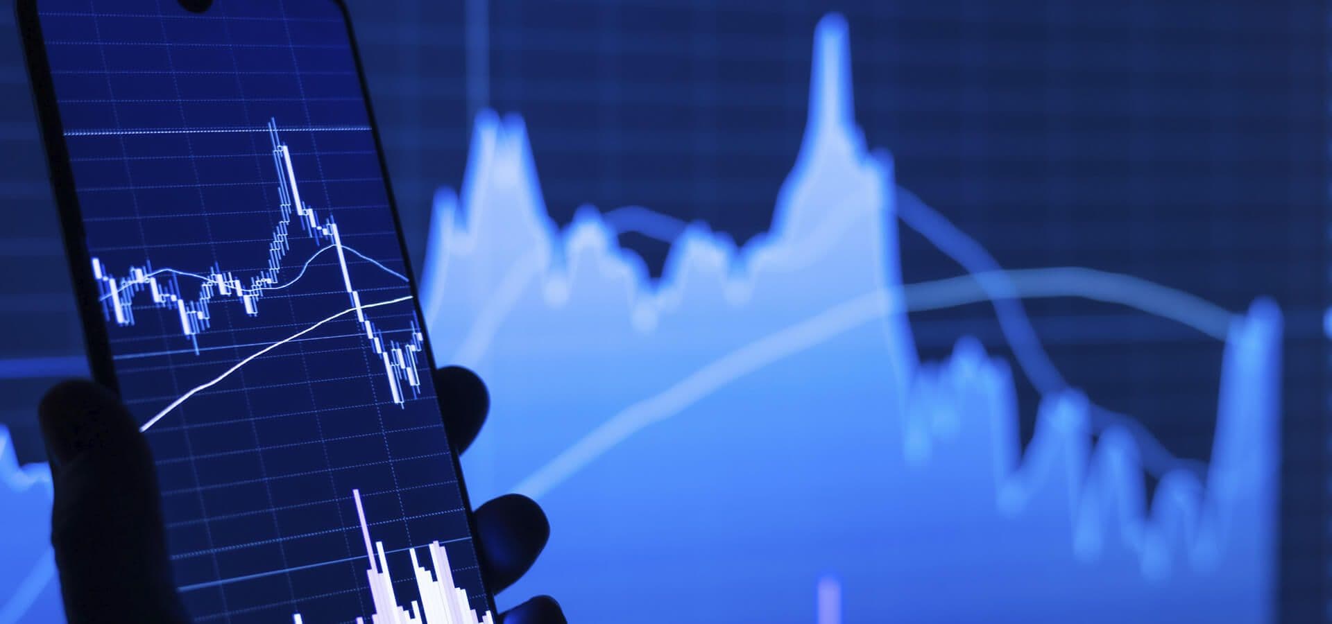 Gráfico de bolsa con un móvil sujetado por una mano